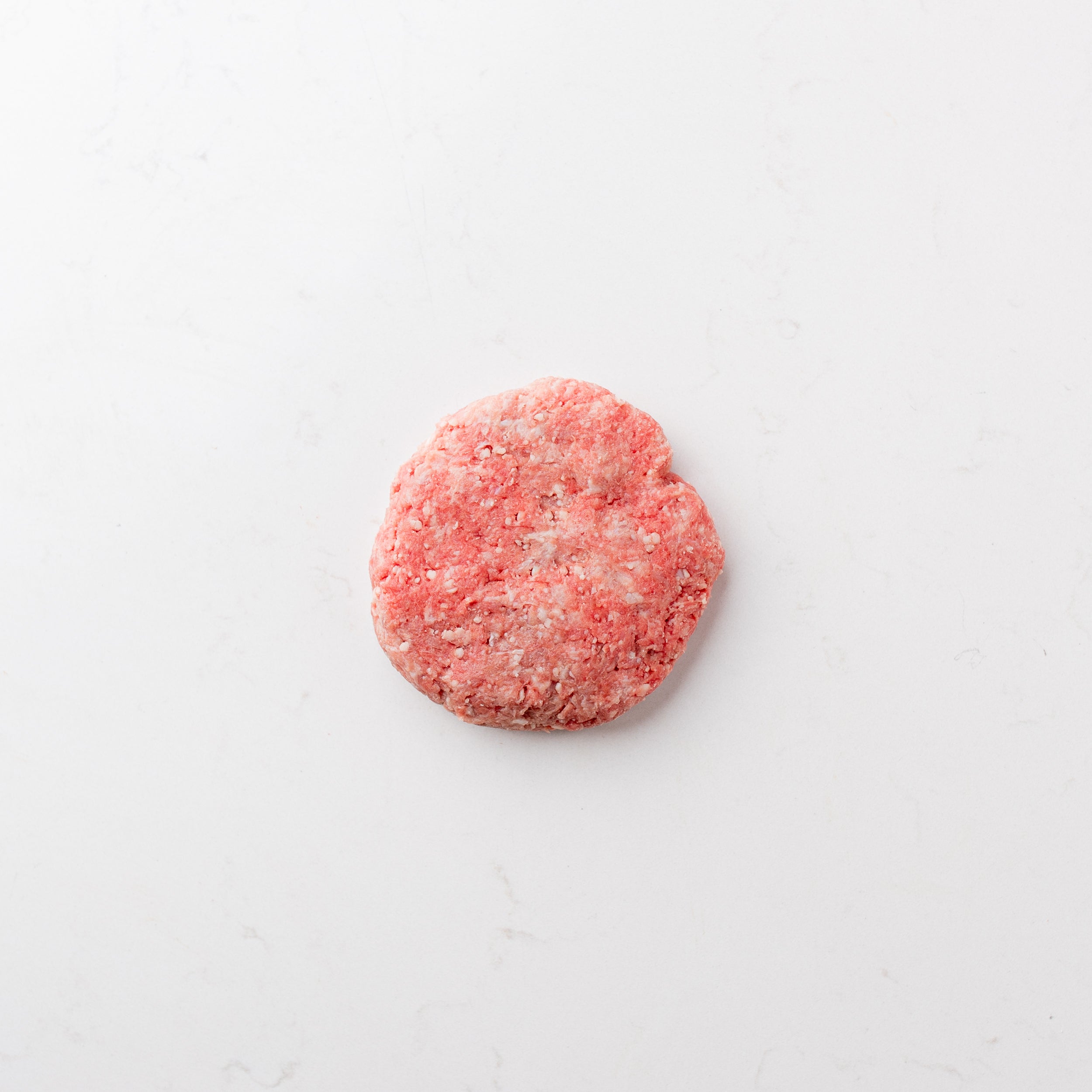 raw hamburger patties arranged on a white surface.